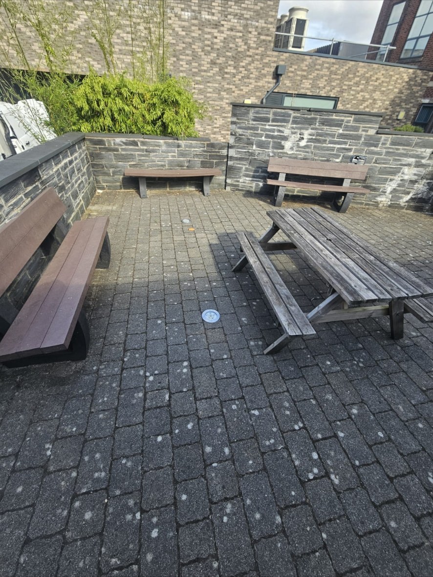 Darkened block paving in a commercial seating courtyard before cleaning